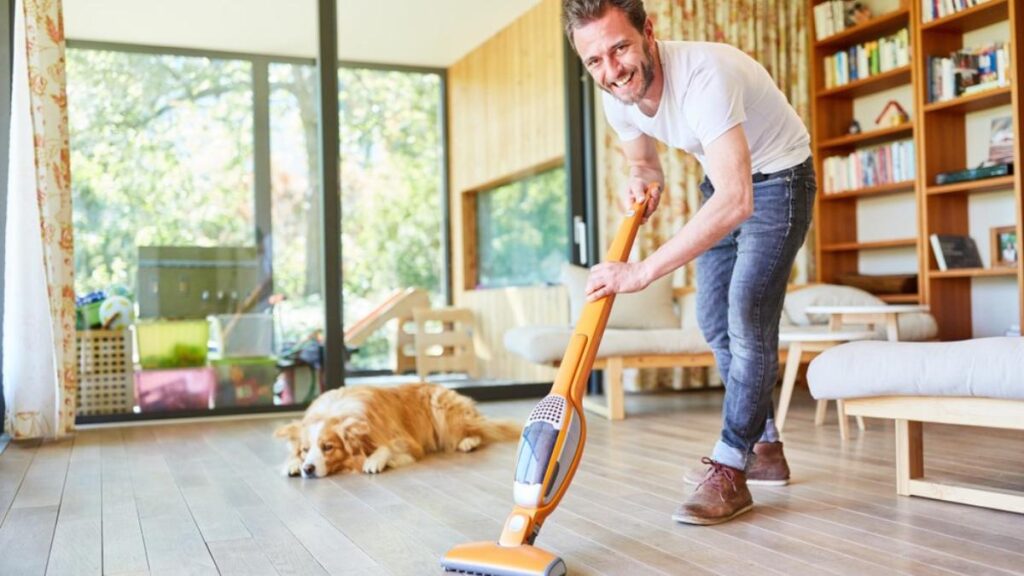 guy with dog vacuuming floor