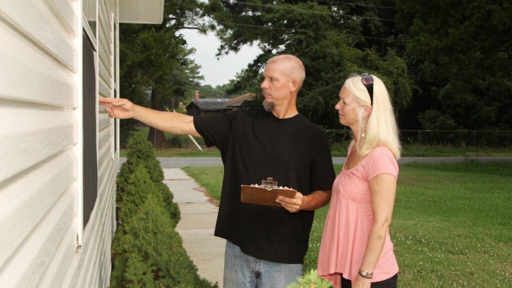 home inspector and homeowner inspecting a window