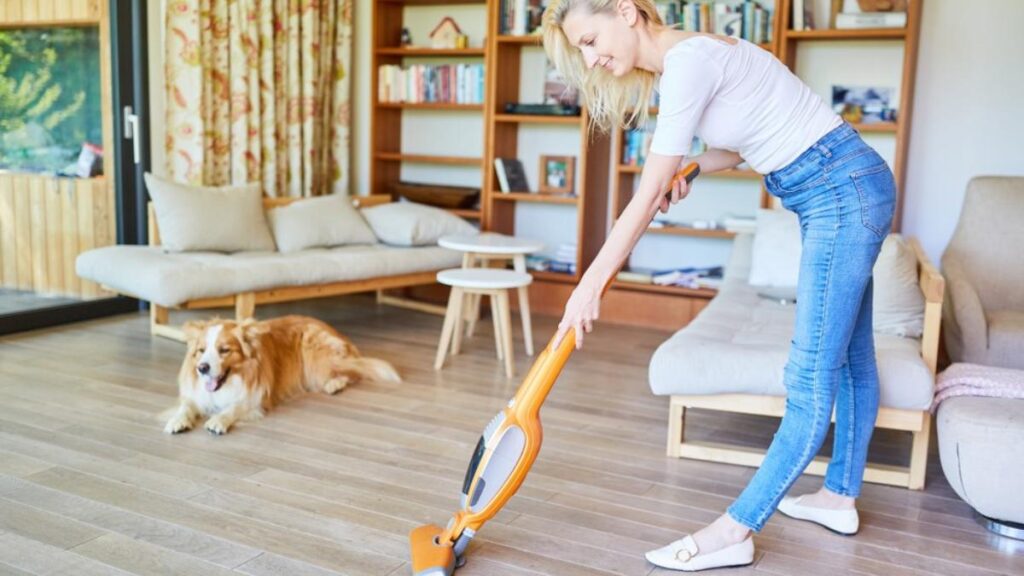 girl with dog vacuuming floor