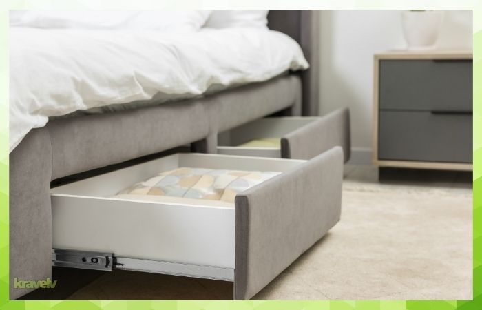 Under-bed storage drawers used to organize clothes and linens in a compact bedroom.