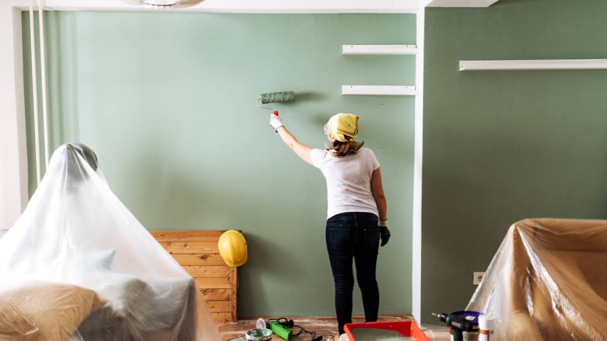 girl painting the wall green