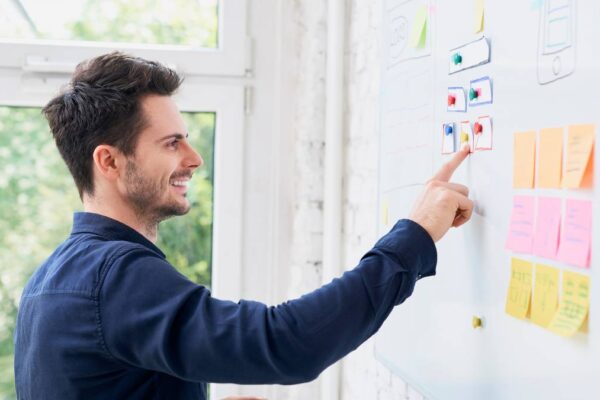 Guy arranging notes in a whiteboard-painted writable wall in a home office