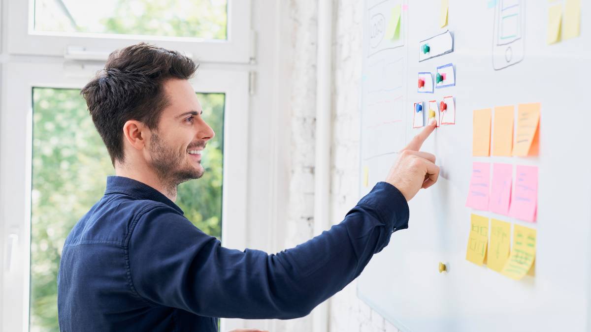 Guy arranging notes in a whiteboard-painted writable wall in a home office