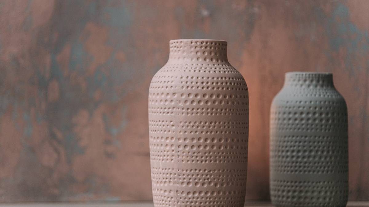 big and small ceramic vase displayed on a mud colored wall